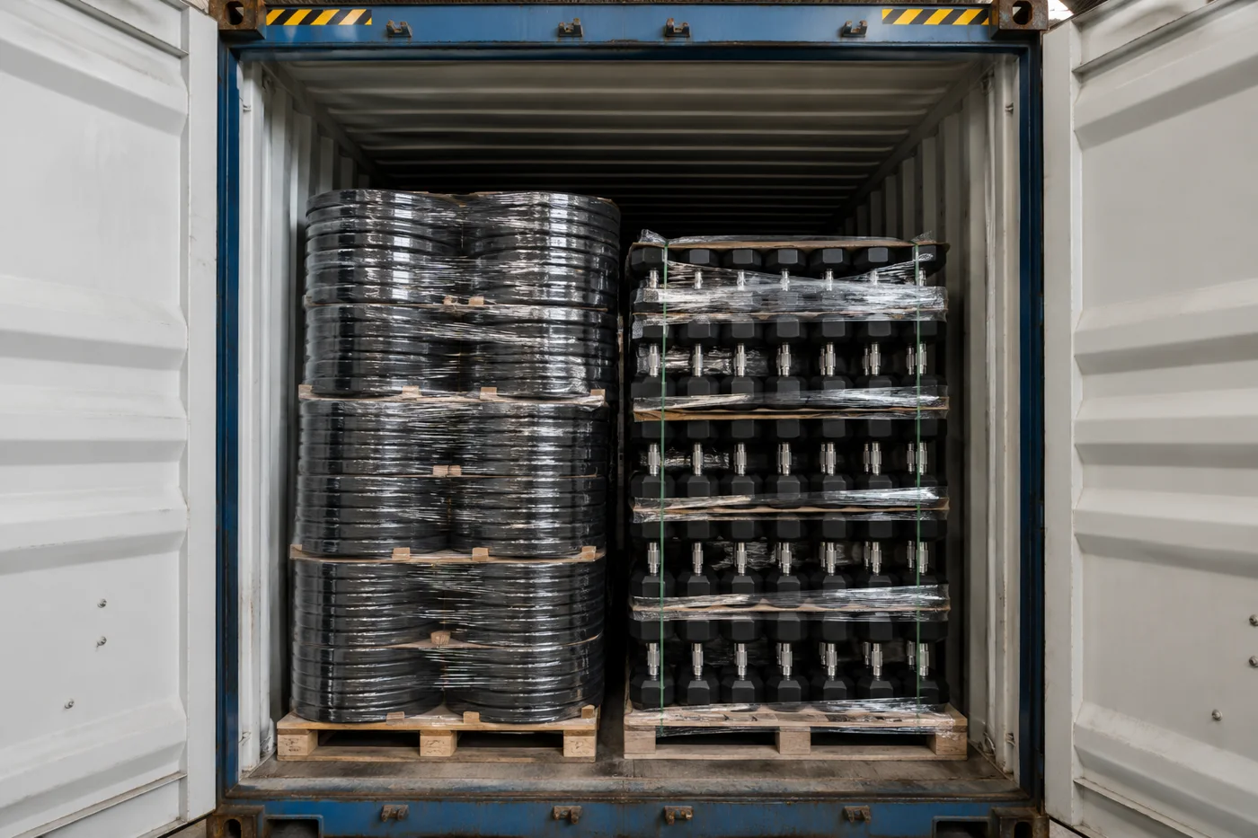 Weight plates and dumbbells loaded into a shipping container for export